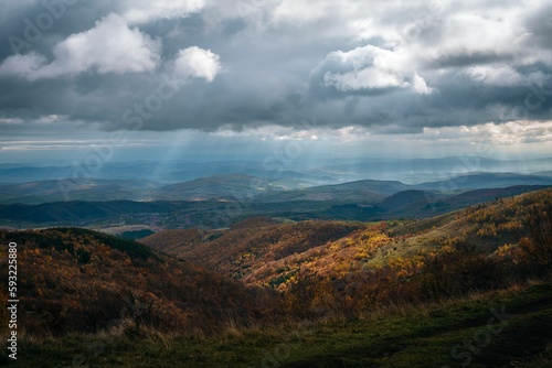 Big mountains covered in yellow forests under the gloomy autumn sky