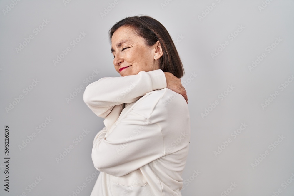 Middle age hispanic woman standing over isolated background hugging oneself happy and positive, smiling confident. self love and self care Middle age hispanic woman standing over isolated background hugging oneself happy and positive, smiling confident. self love and self care