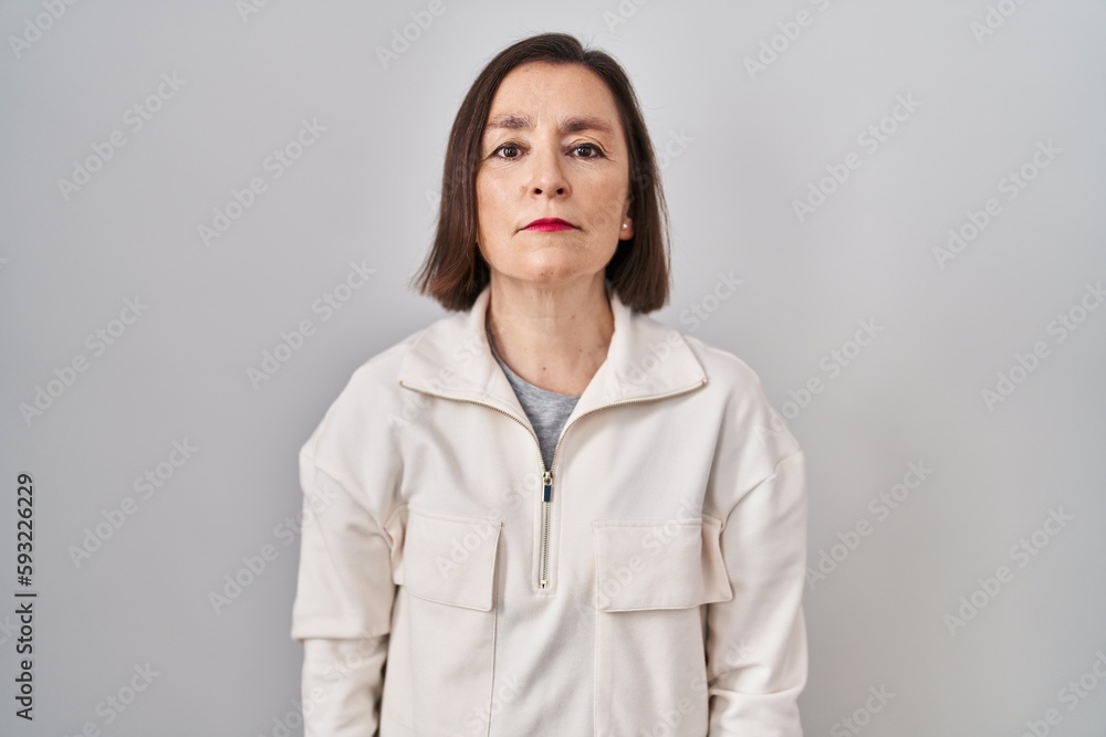 Middle age hispanic woman standing over isolated background relaxed with serious expression on face. simple and natural looking at the camera. Middle age hispanic woman standing over isolated background relaxed with serious expression on face. simple and natural looking at the camera.