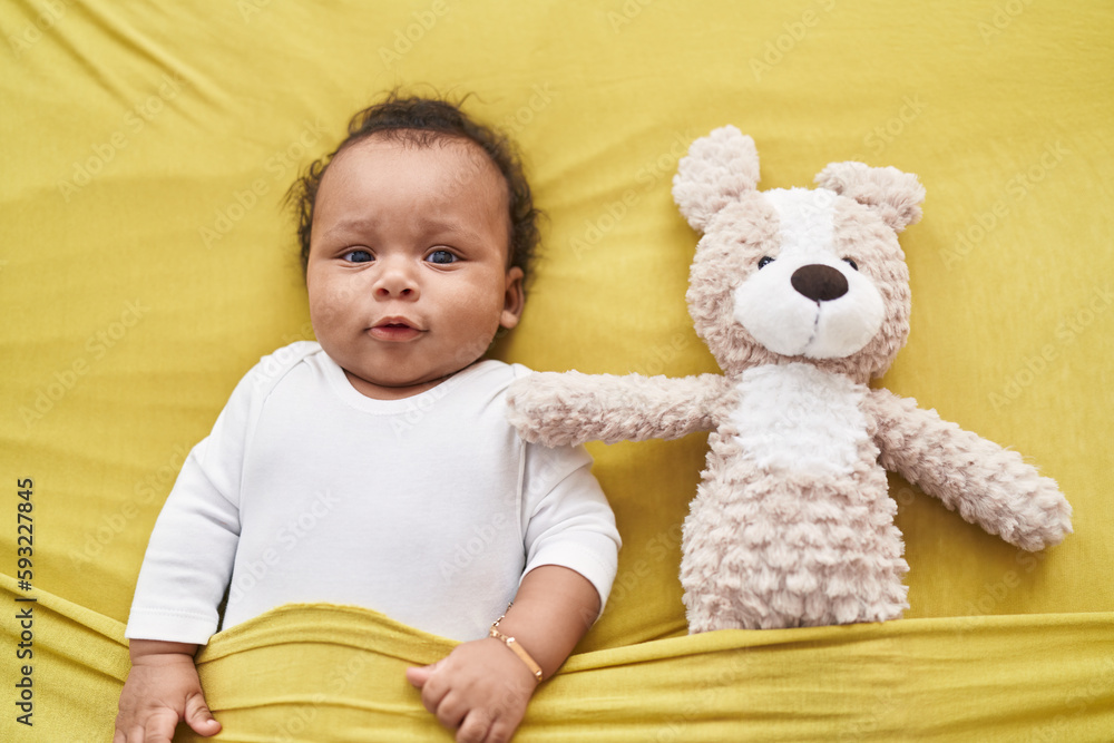 African american baby relaxing on bed with teddy bear at bedroom African american baby relaxing on bed with teddy bear at bedroom