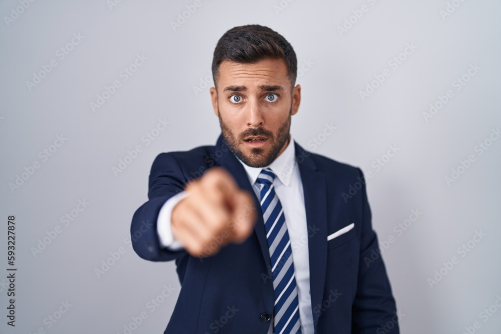 Handsome hispanic man wearing suit and tie pointing displeased and frustrated to the camera, angry and furious with you Handsome hispanic man wearing suit and tie pointing displeased and frustrated to the camera, angry and furious with you