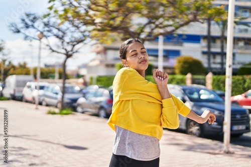 Young african american woman smiling confident stretching at street