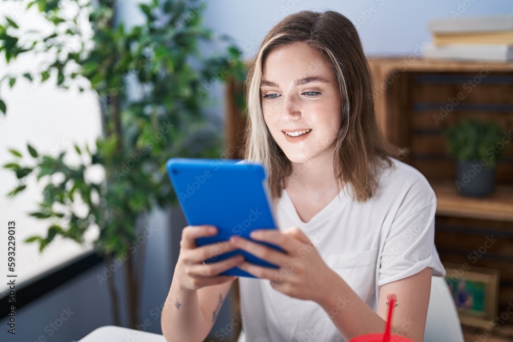 Young woman using touchpad sitting on table at home Young woman using touchpad sitting on table at home