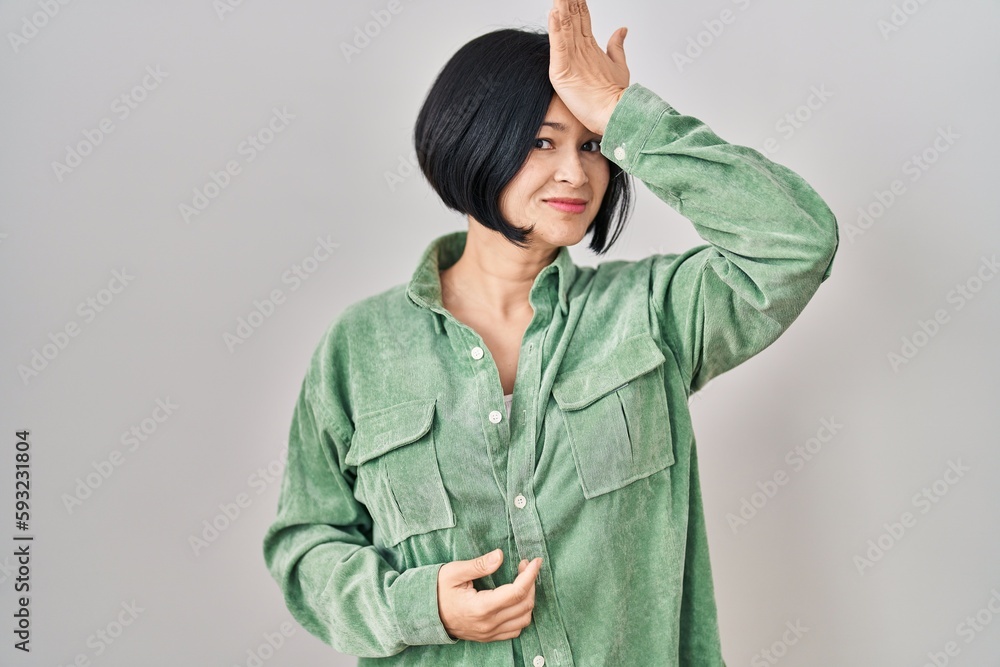 Young asian woman standing over white background surprised with hand on head for mistake, remember error. forgot, bad memory concept. Young asian woman standing over white background surprised with hand on head for mistake, remember error. forgot, bad memory concept.