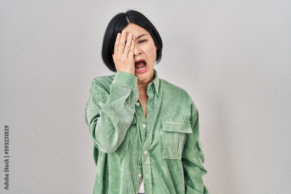 Young asian woman standing over white background yawning tired covering ...
