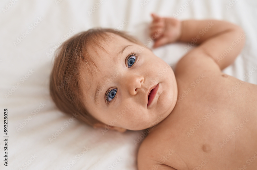 Adorable caucasian baby lying on bed with relaxed expression at bedroom Adorable caucasian baby lying on bed with relaxed expression at bedroom