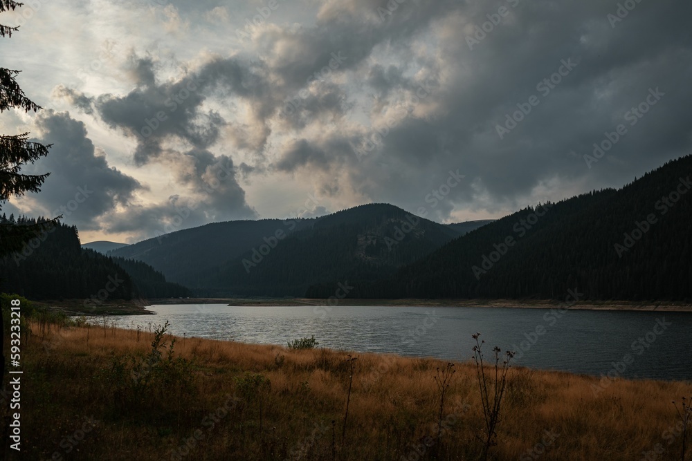 Mesmerizing landscape view with mountains and calm lake water against a cloudy sky
