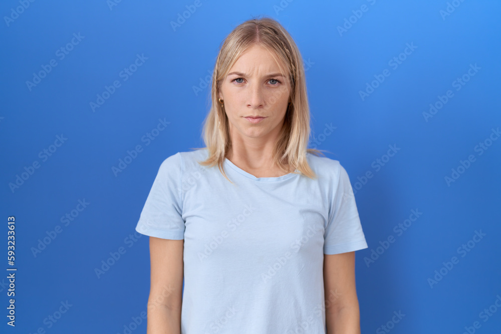 Young caucasian woman wearing casual blue t shirt skeptic and nervous, frowning upset because of problem. negative person. Young caucasian woman wearing casual blue t shirt skeptic and nervous, frowning upset because of problem. negative person.