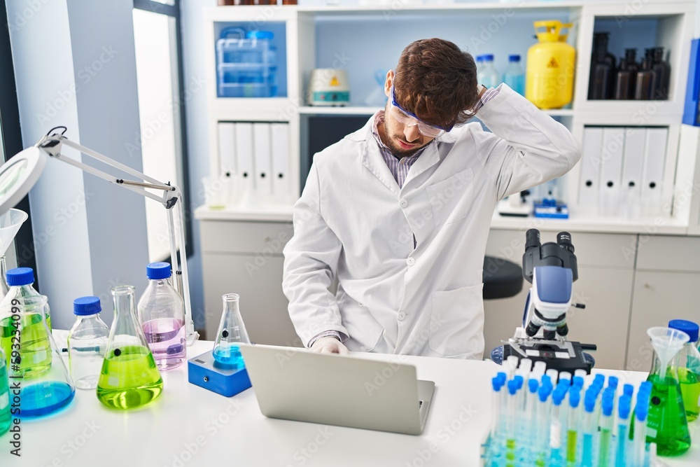 Young arab man scientist stressed using laptop working at laboratory Young arab man scientist stressed using laptop working at laboratory