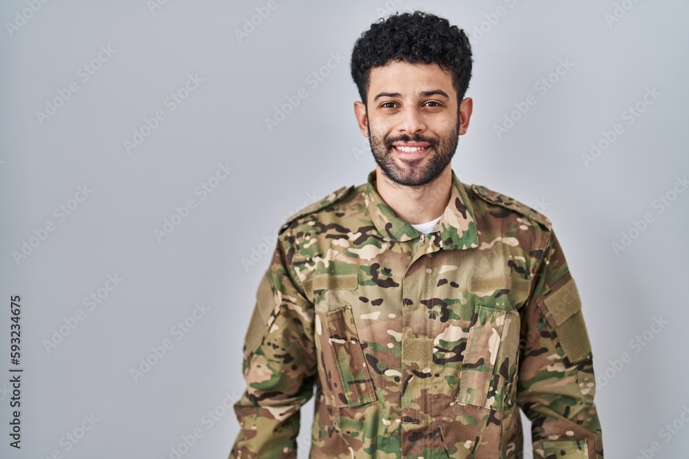 Arab man wearing camouflage army uniform with a happy and cool smile on face. lucky person.