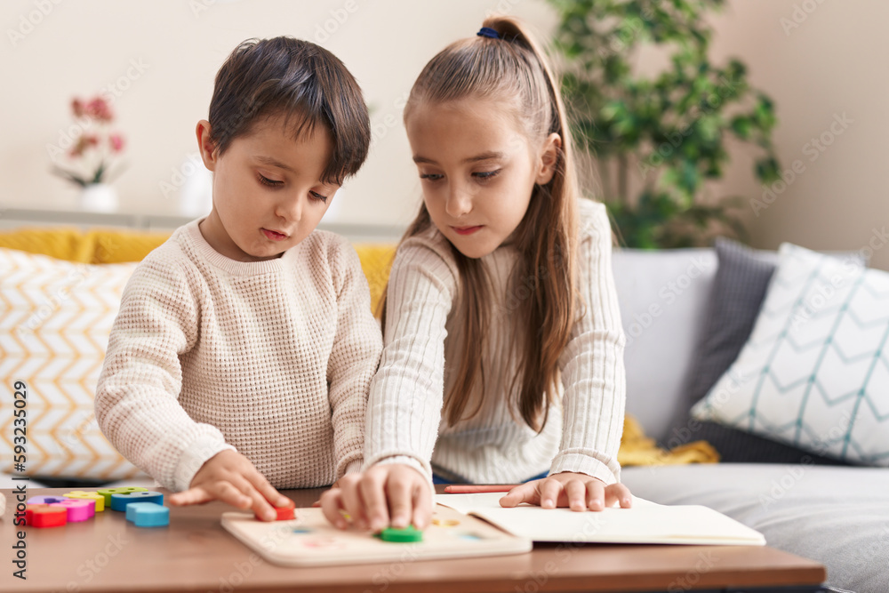 Adorable boy and girl playing with maths puzzle game standing at home Adorable boy and girl playing with maths puzzle game standing at home