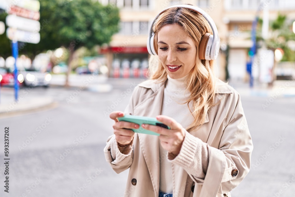 Young blonde woman smiling confident playing video game at street Young blonde woman smiling confident playing video game at street