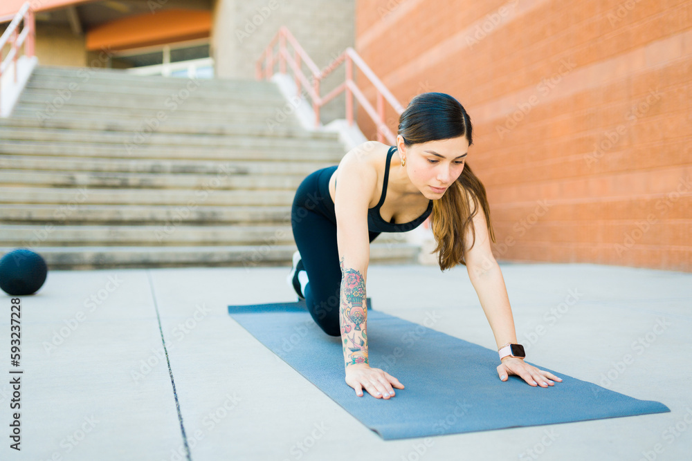Fototapeta premium Fit latin woman exercising with mountain climbers outdoors