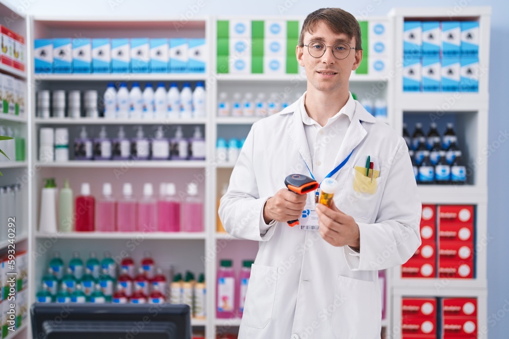 Young caucasian man pharmacist scanning pills bottle at pharmacy