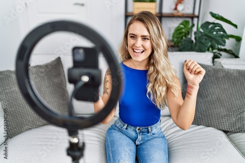 Young woman recording makeup tutorial by smartphone at home