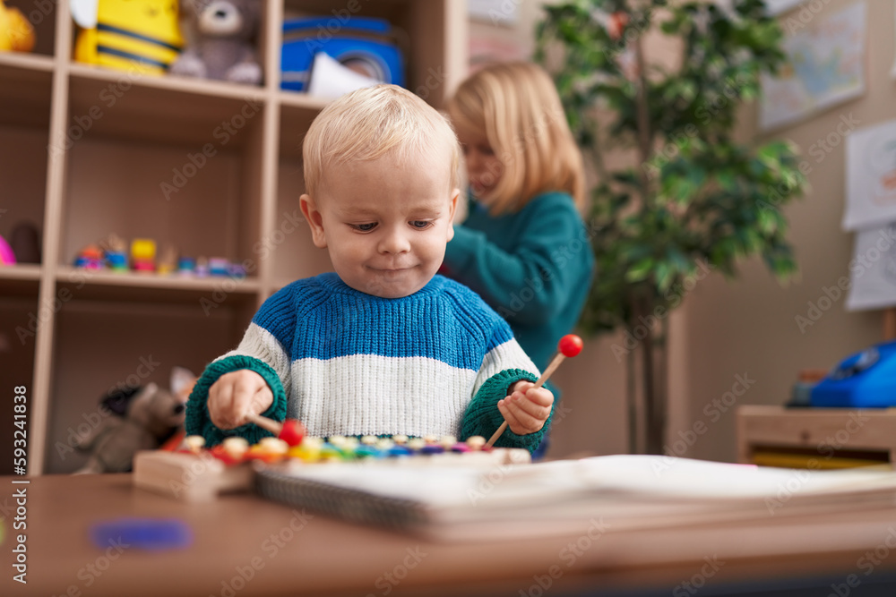 Adorable boy and girl playing xylophone standing at kindergarten Adorable boy and girl playing xylophone standing at kindergarten