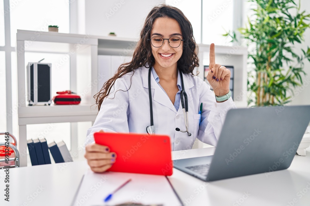 Young doctor woman working on online appointment smiling with an idea or question pointing finger with happy face, number one Young doctor woman working on online appointment smiling with an idea or question pointing finger with happy face, number one