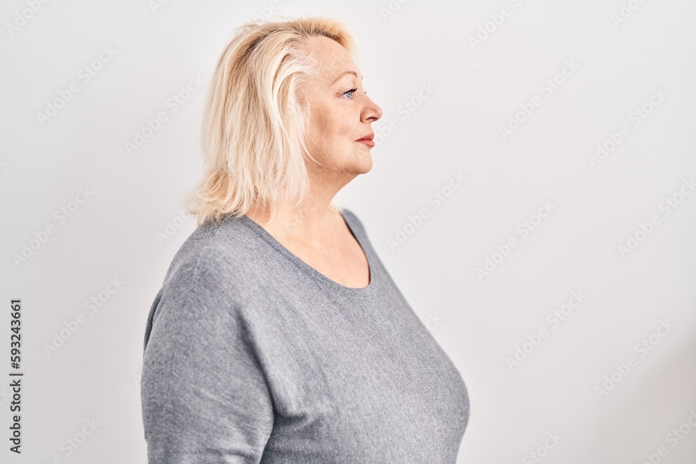 Middle age caucasian woman standing over white background looking to side, relax profile pose with natural face and confident smile. Middle age caucasian woman standing over white background looking to side, relax profile pose with natural face and confident smile.