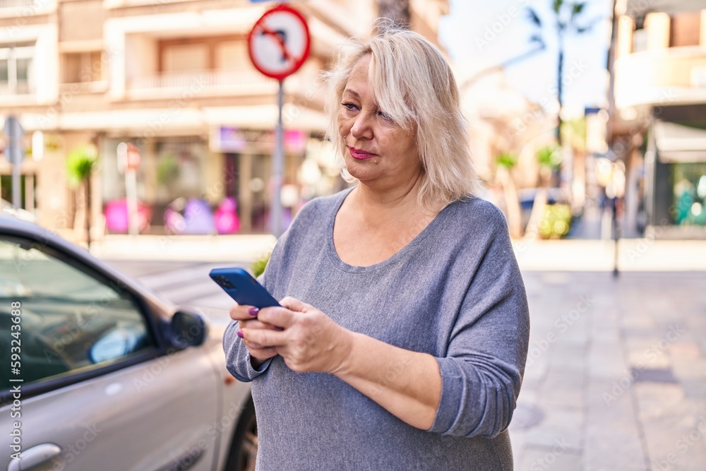 Middle age blonde woman using smartphone at street Middle age blonde woman using smartphone at street