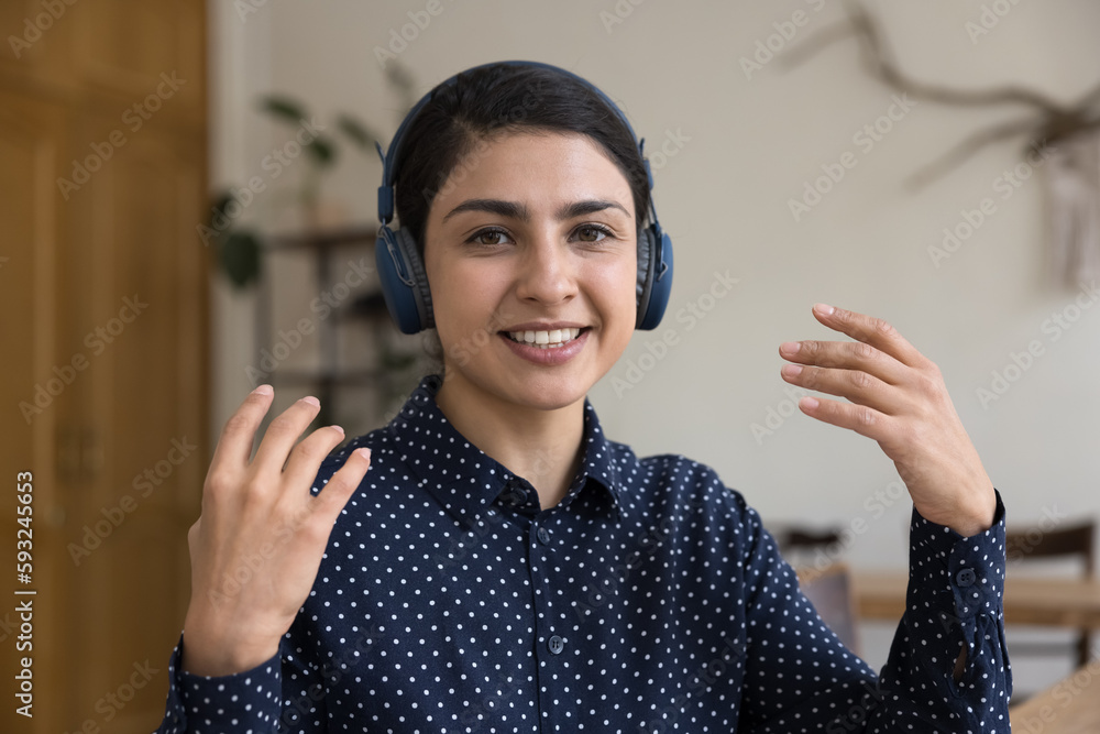 Young Indian woman, female on-line counsellor provide help, information to client remotely, wear headphones make speech, teach to learner, use videoconference app, head shot, webcam view. Videocall