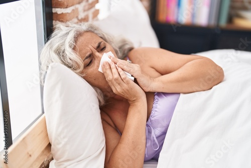 Middle age grey-haired woman lying on bed illness at bedroom