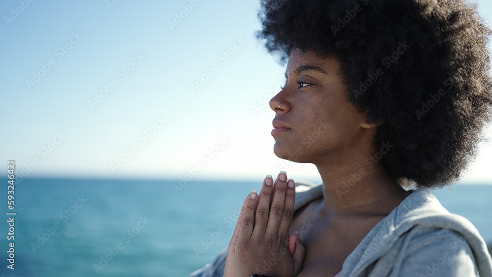 African american woman praying at seaside
