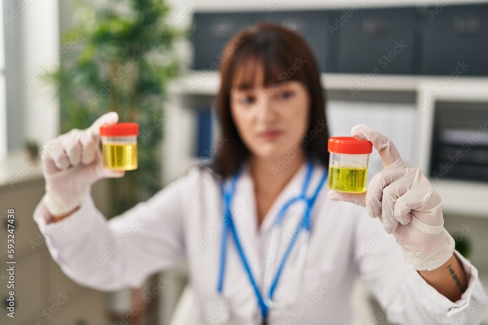 Young beautiful hispanic woman doctor comparing urine test tubes at clinic Young beautiful hispanic woman doctor comparing urine test tubes at clinic