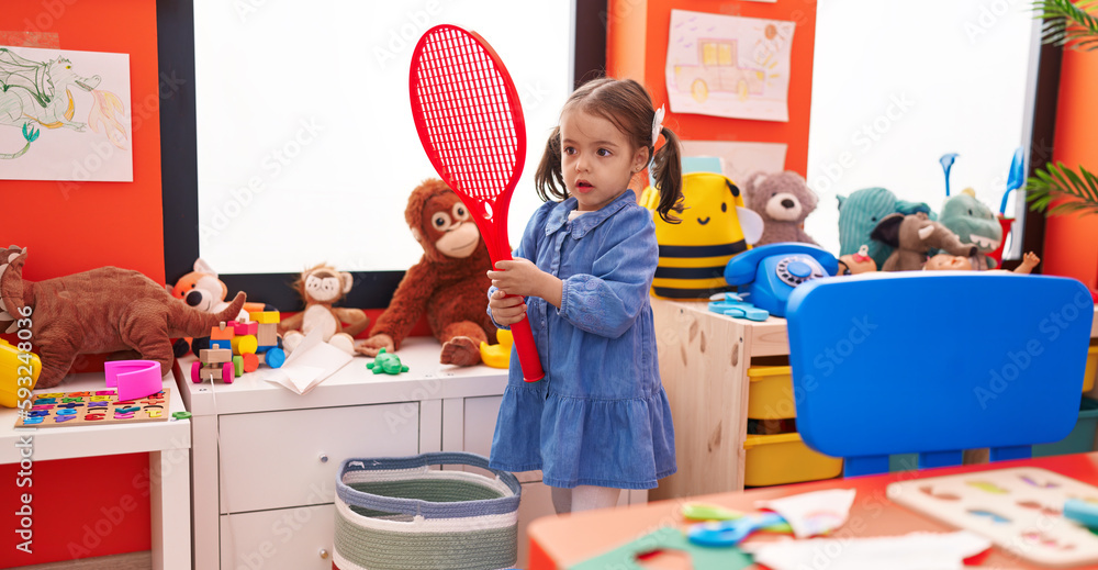 Adorable hispanic girl playing with tennis racket at kindergarten Adorable hispanic girl playing with tennis racket at kindergarten