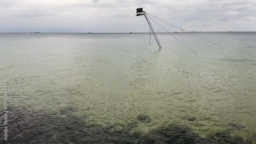 Crane for pulling fishing boats at sea. Cloudy day by the sea.