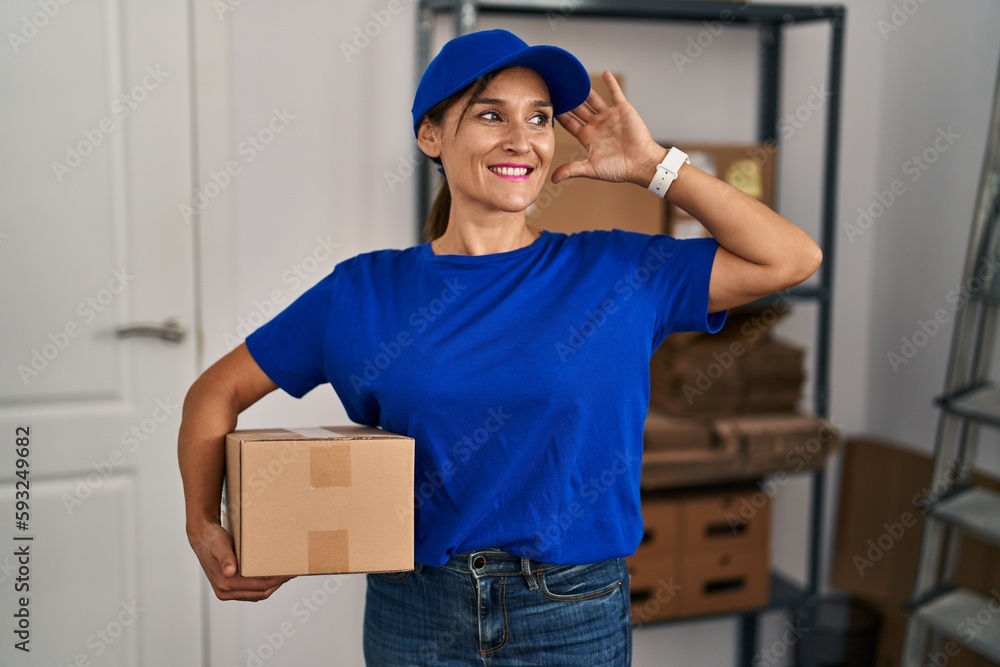 Middle age brunette woman working wearing delivery uniform and cap smiling confident touching hair with hand up gesture, posing attractive and fashionable Middle age brunette woman working wearing delivery uniform and cap smiling confident touching hair with hand up gesture, posing attractive and fashionable