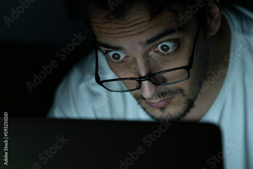 Close up of shocked man looking at laptop at the night time 