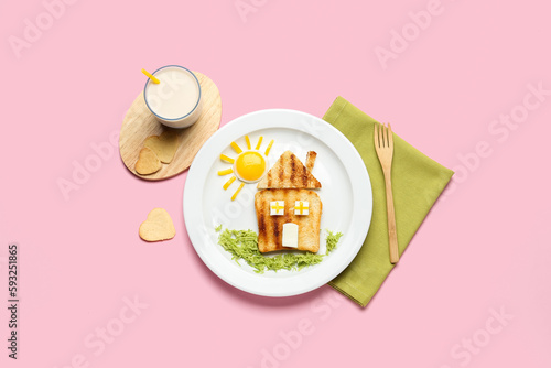 Plate with funny children's breakfast in shape of house and glass of milk on pink background photo