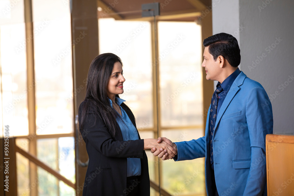 Young indian businesswoman shake hand with businessman at office.