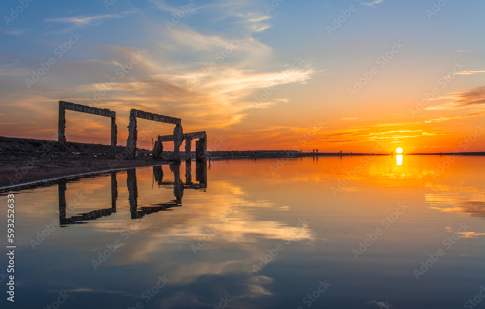 sunset at coast of the lake. Nature landscape. Nature in North Africa. reflection, blue sky and yellow sunlight. landscape during sunset, Silhouette reflection of the remains of an abandoned house.