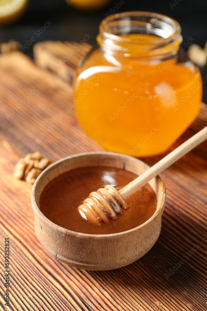 Fototapeta premium Golden honey in wooden bowl with dipper and jar on rustic wood board, natural sweetener and healthy food