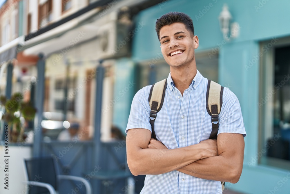 Young hispanic man student smiling confident standing with arms crossed gesture at street Young hispanic man student smiling confident standing with arms crossed gesture at street