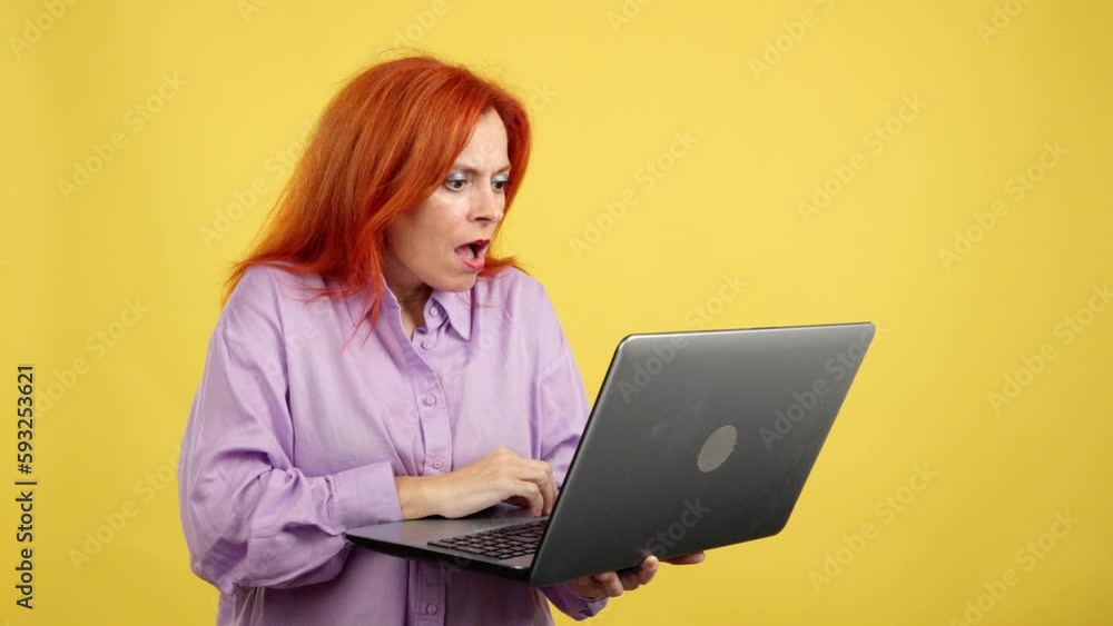 Redheaded mature woman with a surprised look using a laptop Redheaded mature woman with a surprised look using a laptop