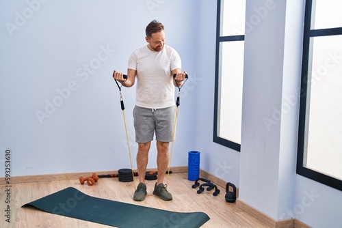 Young caucasian man smiling confident using elastic band training at sport center