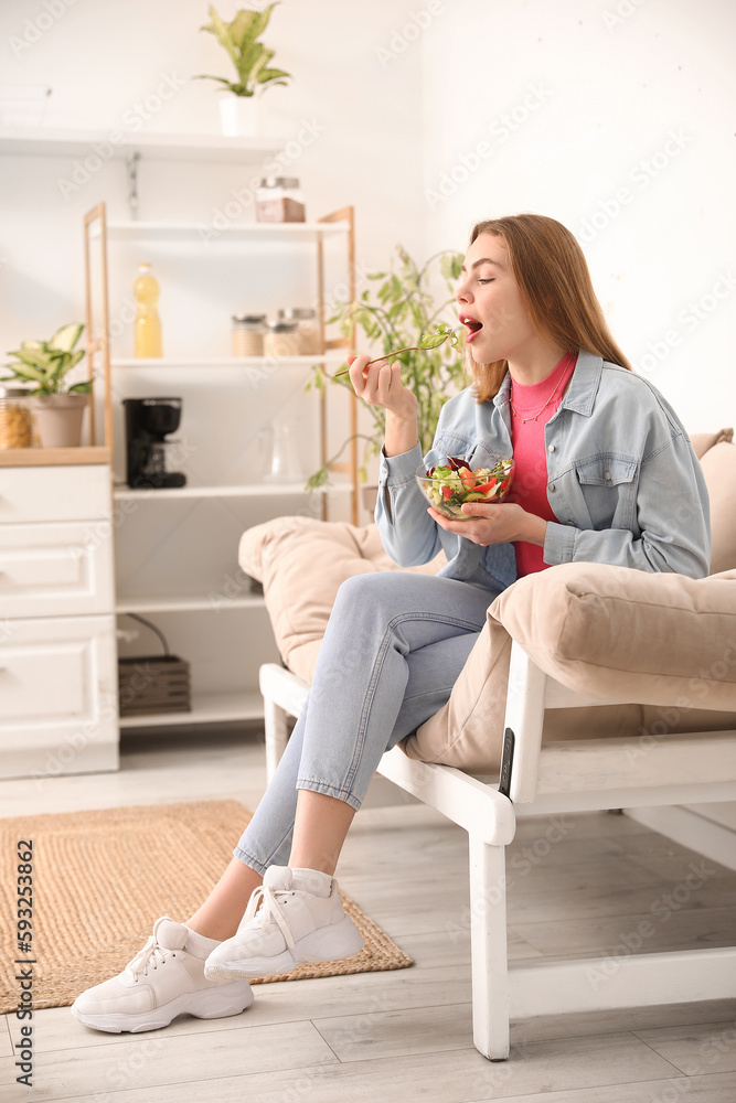 Young woman eating vegetable salad on sofa at home Young woman eating vegetable salad on sofa at home