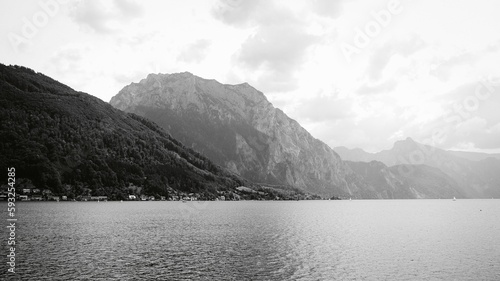 Grayscale of the calm lake with the big mountains in the background in Gmunden, Austria