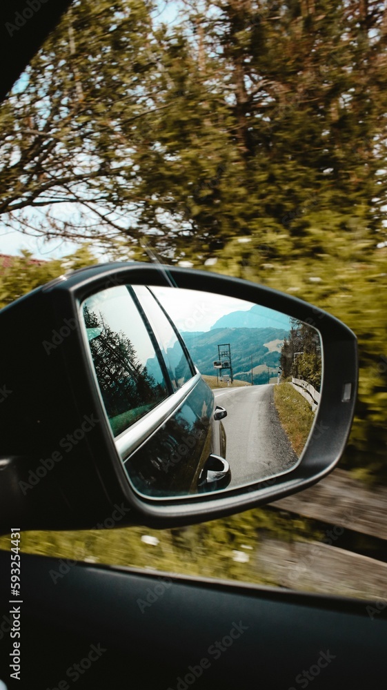 Vertical shot of the side mirror of a car with the road reflected in it Vertical shot of the side mirror of a car with the road reflected in it