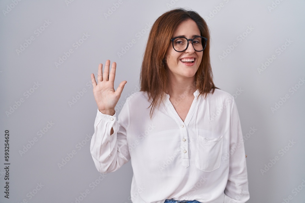 Brunette woman standing over white isolated background waiving saying hello happy and smiling, friendly welcome gesture Brunette woman standing over white isolated background waiving saying hello happy and smiling, friendly welcome gesture