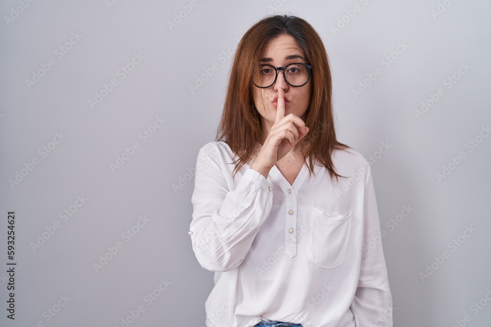 Brunette woman standing over white isolated background asking to be quiet with finger on lips. silence and secret concept. Brunette woman standing over white isolated background asking to be quiet with finger on lips. silence and secret concept.