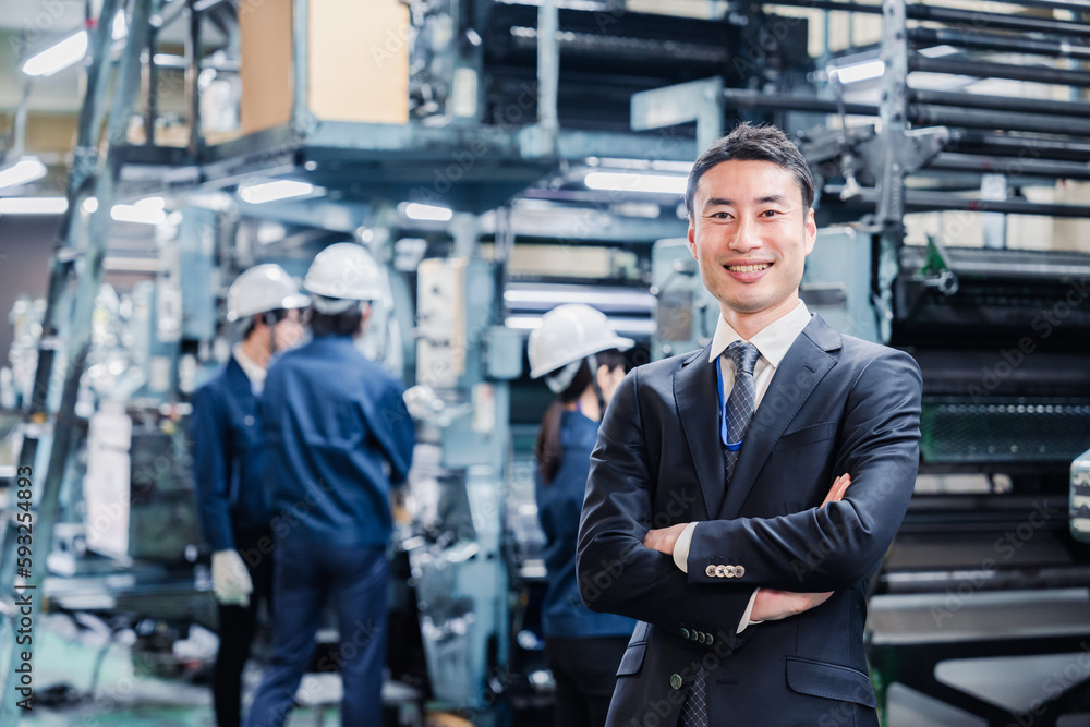 工場で腕を組むホワイトカラーの男性