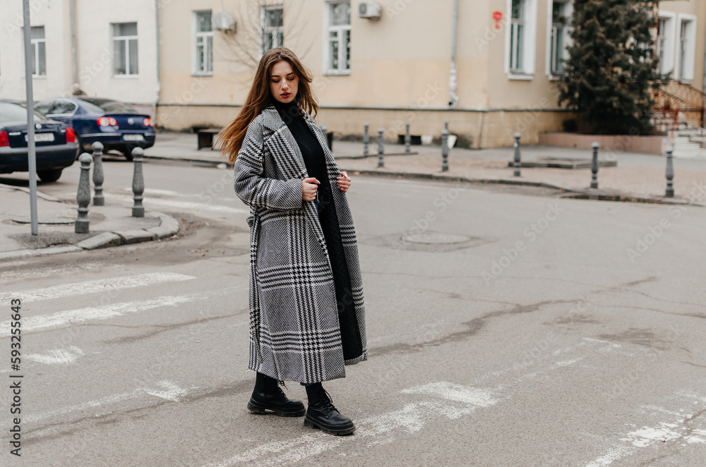 Naklejka premium A woman crossing the street in a coat and jeans