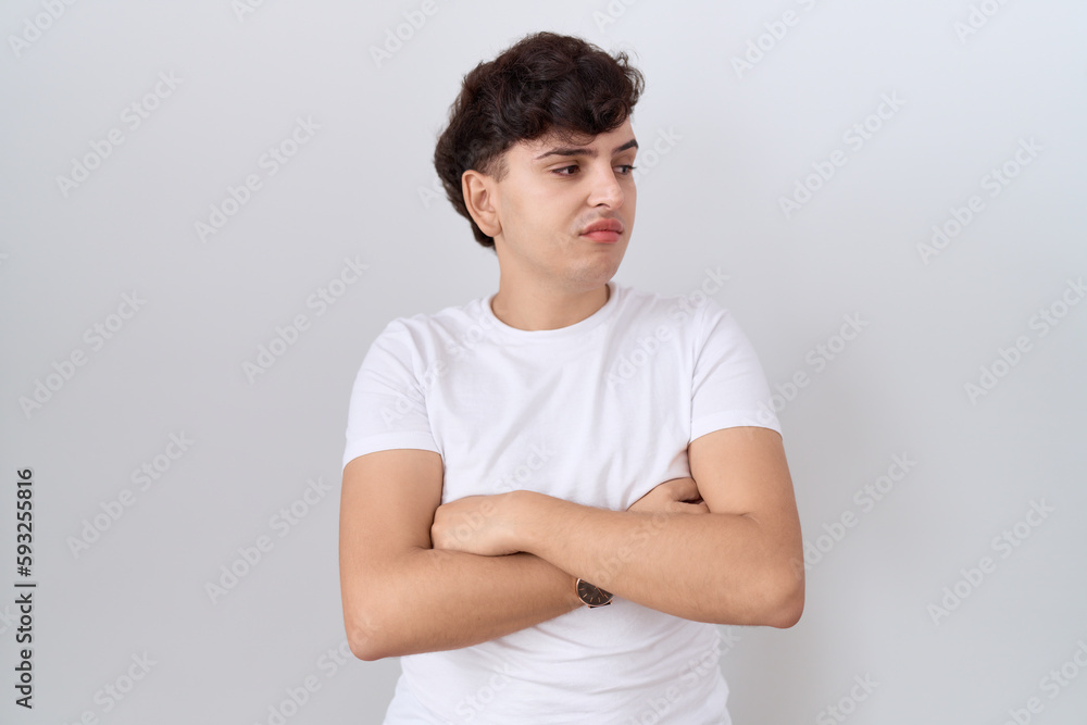 Young non binary man wearing casual white t shirt looking to the side with arms crossed convinced and confident Young non binary man wearing casual white t shirt looking to the side with arms crossed convinced and confident