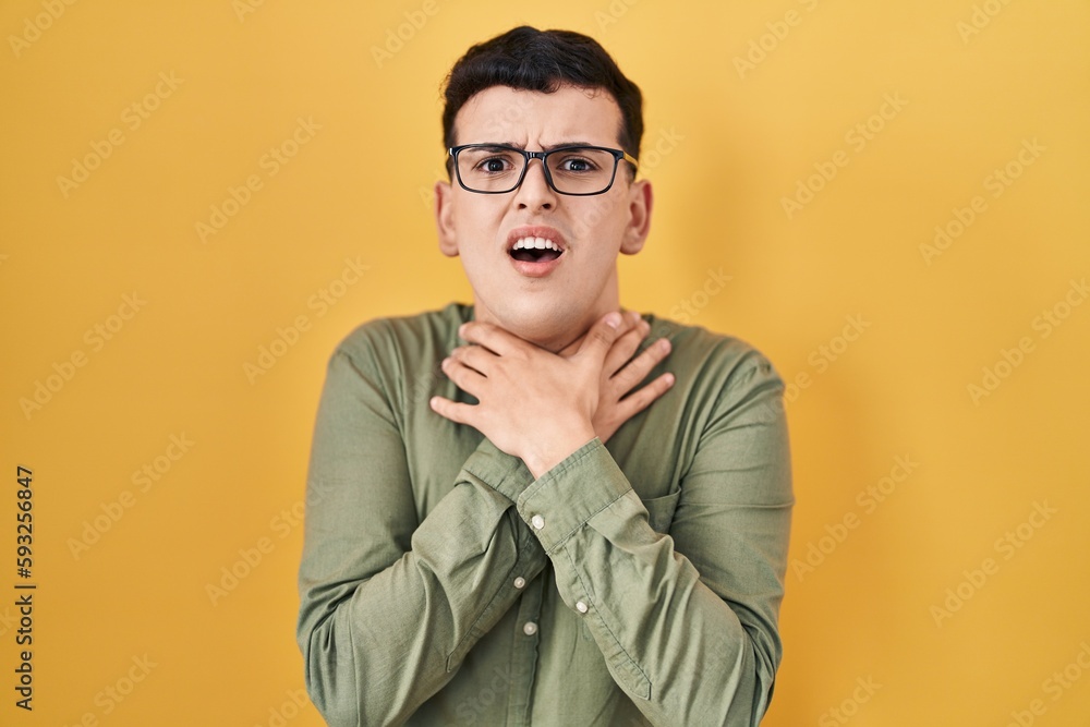 Obraz premium Non binary person standing over yellow background shouting and suffocate because painful strangle. health problem. asphyxiate and suicide concept.