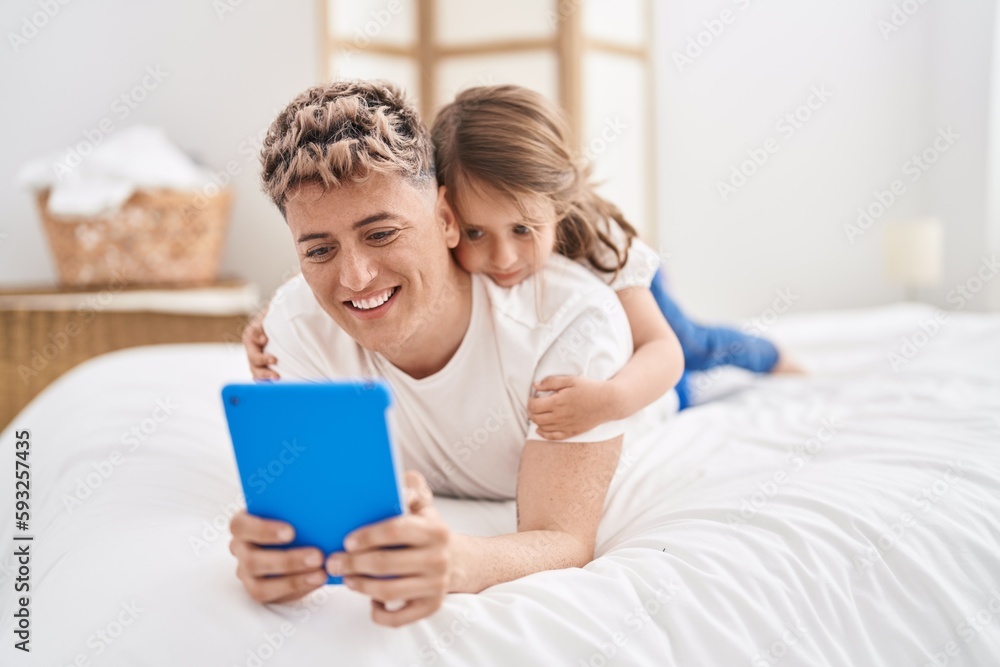 Father and daughter father and daughter using touchpad lying on bed at bedroom Father and daughter father and daughter using touchpad lying on bed at bedroom
