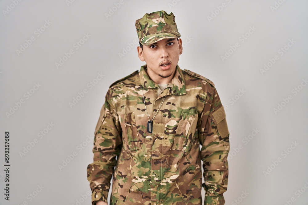 Young arab man wearing camouflage army uniform in shock face, looking skeptical and sarcastic, surprised with open mouth Young arab man wearing camouflage army uniform in shock face, looking skeptical and sarcastic, surprised with open mouth