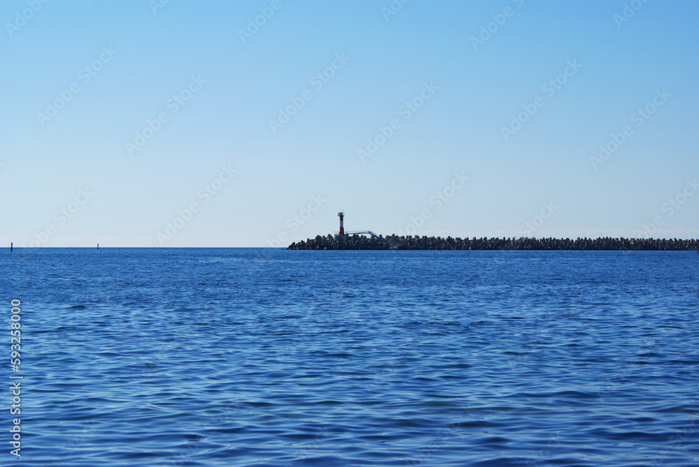 View of the lighthouse in the sea, resort embankment, sun glare on the water, background View of the lighthouse in the sea, resort embankment, sun glare on the water, background